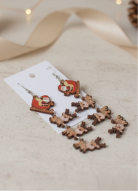 Close-up of Santa sleigh and reindeer earrings laid flat on card, showing printed detail