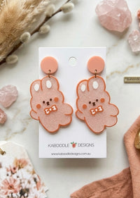 Pink glitter kawaii bunny drop earrings with bow ties on a Kaboodle Designs card