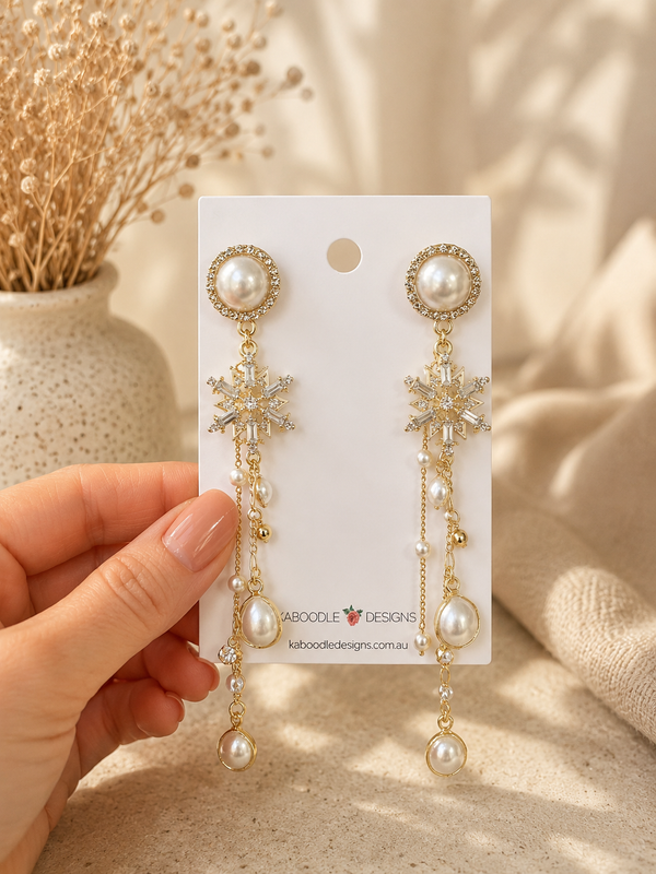 Gold snowflake pearl drop earrings displayed on a Kaboodle Designs card