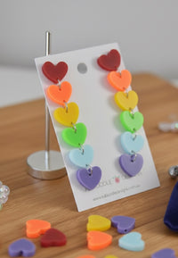 Rainbow heart drop earrings on a Kaboodle Designs card, showing six graduated coloured acrylic hearts per earring