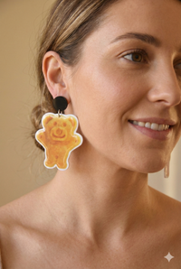 Close-up of Tiny Teddy earring worn on ear, showing biscuit bear design and black stud top