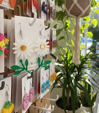 Daisy flower earrings displayed on retail hook alongside other novelty earrings