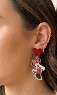Close-up of glitter Minnie Mouse dangle earring with red heart detail worn on a model's ear