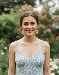 Model wearing caramel bunny drop earrings outdoors in a garden setting
