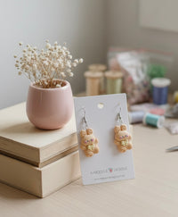 Bunny drop earrings displayed on card beside dried flowers and craft supplies