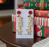 Gingerbread earrings on card resting on table beside wrapped Christmas presents