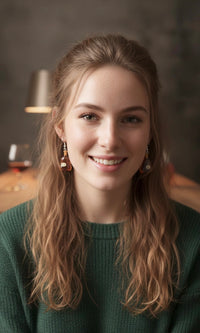 Woman wearing amber brandy bottle earrings, close-up on face with earrings visible near jaw