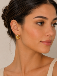 Close-up of gold hoop earring with crystal detail worn on model's ear