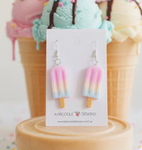 Pink, yellow and blue ombre popsicle resin earrings on Kaboodle Designs card against ice cream cone backdrop
