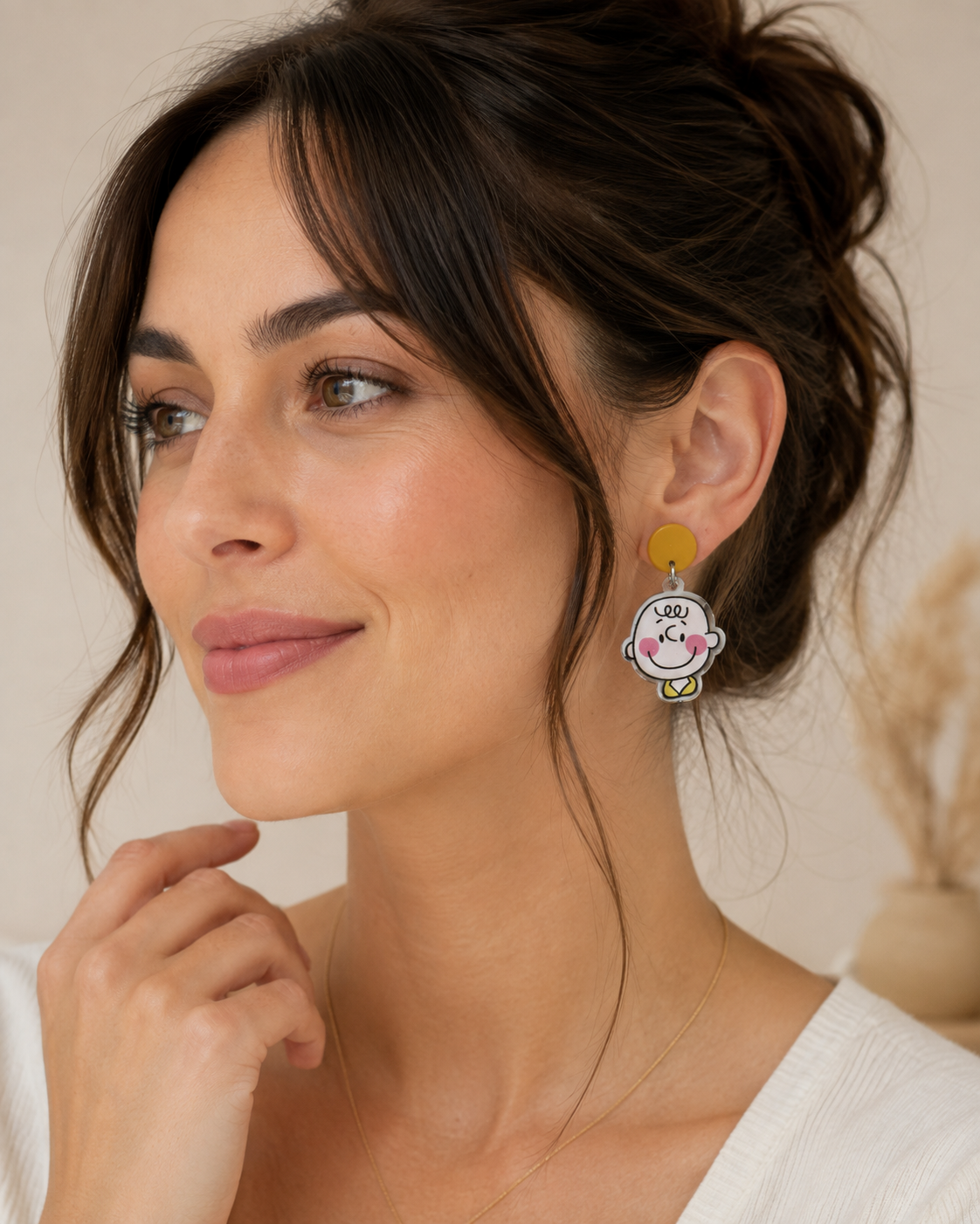 Close-up of a woman wearing a mustard stud and cartoon boy face drop earring