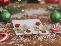 Rudolf reindeer earrings laid flat on wooden table with candy canes and snow
