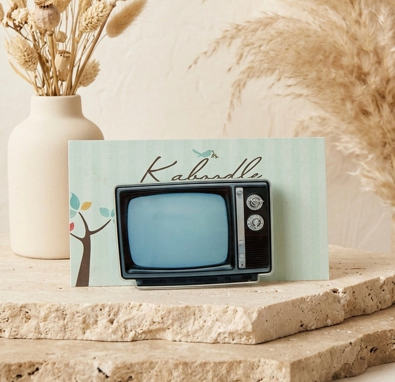 Retro-style television brooch shaped like an old box TV set with black frame, blue screen and side dials