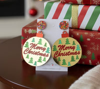 Pair of gold bauble-shaped Merry Christmas drop earrings on card, propped against wrapped presents