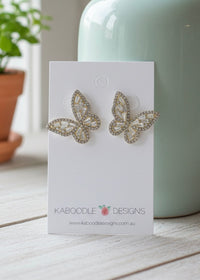 Pair of gold-toned rhinestone butterfly stud earrings displayed on a white Kaboodle Designs card