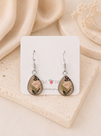 Teardrop earrings on card featuring pink floral print sealed in glossy resin, pair shown together