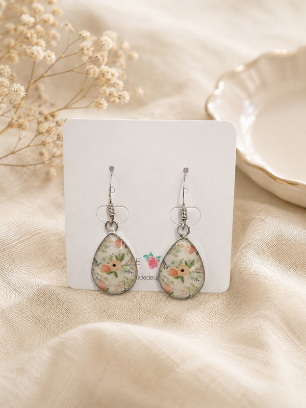 Teardrop floral dangle earrings on a display card, showing peach and green floral resin print