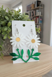 White daisy drop earrings with gold centres and green leaf stems on Kaboodle card