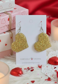 Gold glitter perspex heart drop earrings displayed on white Kaboodle Designs card
