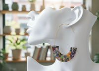 Close-up of terrazzo hoop earring worn on ear, showing gold wire and confetti pattern