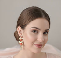 Red heart rhinestone drop earrings worn on model's ear, close-up view
