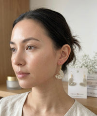 Woman wearing gold diamante heart drop earring, front angle showing rhinestone heart shape