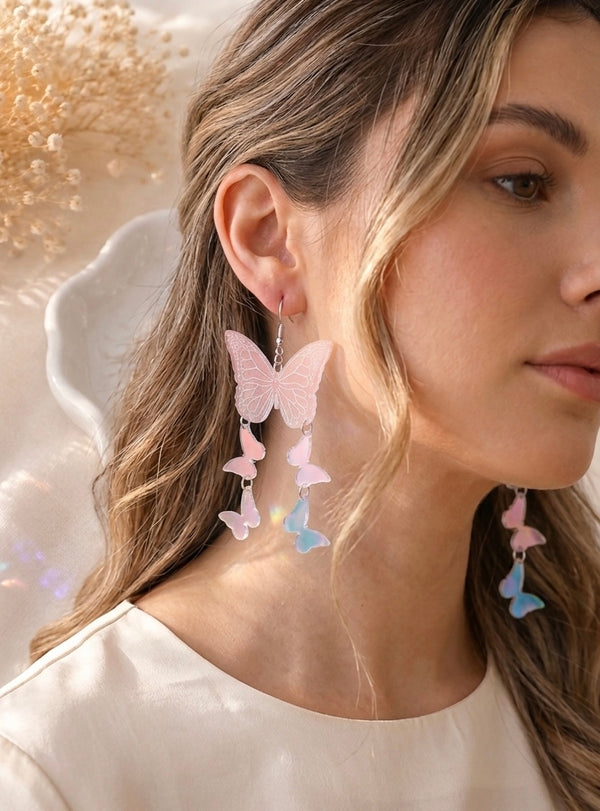 Translucent pink butterfly drop earring worn on ear, showing three cascading butterfly tiers