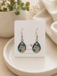 Teardrop earrings on card with teal floral print featuring pink and white flowers