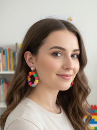 Close-up of woman wearing rainbow star hoop earring with pearl stud top, side profile view