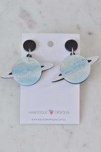 Pair of blue glittery Saturn planet drop earrings with pearly rings on Kaboodle card