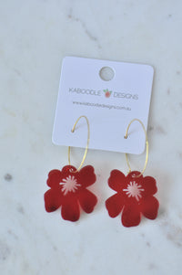 Red acrylic poppy flower earrings on gold hoops, displayed on Kaboodle Designs card