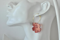 Close-up of red poppy earring worn on ear showing gold hoop and starburst centre