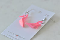 Hot pink stiletto heel earrings lying flat showing pointed toe and thin heel detail