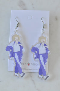 Pair of acrylic drop earrings printed with a figure in a purple tracksuit, on Kaboodle Designs card
