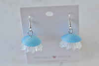 Blue jellyfish earrings on display card against a plain background