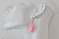 Close-up of hot pink stiletto earring worn on ear against a mannequin head
