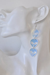 Close-up of one alien drop earring worn on ear, showing iridescent finish