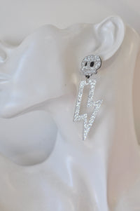 Close-up of glitter lightning bolt skull earring worn on ear, side angle