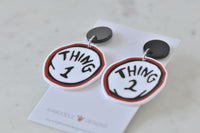 Thing 1 and Thing 2 earrings angled on card, showing black studs and silver connector rings