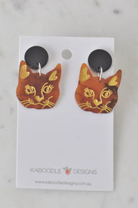 Tortoiseshell cat face drop earrings with gold whisker detail on card backing