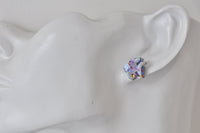 Close-up of a single rainbow fish stud earring worn on an ear