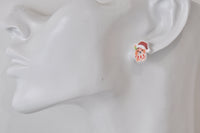 Close-up of corgi Christmas earring in Santa hat and red striped scarf worn on ear
