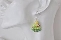 Close-up of green resin Christmas tree earring with star, candy cane and stocking detail