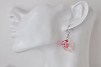Single pink axolotl Santa hat earring shown dangling on ear model