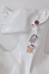 Close-up of Christmas cat drop earring worn on ear showing white, grey and ginger cat charms