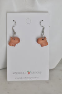 Pair of resin capybara head earrings on Kaboodle Designs card, front view