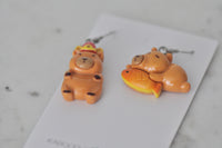 Overhead view of both capybara charms showing glossy resin finish and painted detail