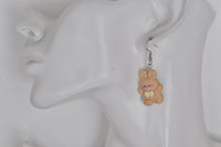 Close-up of pink bunny earring worn on ear showing painted face detail