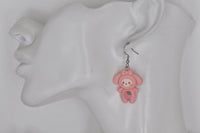 Close-up of pink bunny strawberry earring worn on a model's ear against a white bust