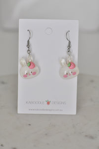 Pair of resin bunny drop earrings with pink strawberry detail on white card backing