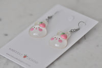 Close-up angled view of bunny earrings showing glossy resin finish and rosy cheeks